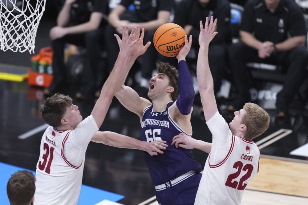Northwestern forward Nick Martinelli (66) drives to the basket on Wisconsin forward Nolan Winter (31) and Steven Crowl (22) during the second half of an NCAA college basketball game in the second round of the Big Ten Conference tournament in Indianapolis, Thursday, March 13, 2025. (AP Photo/Michael Conroy)