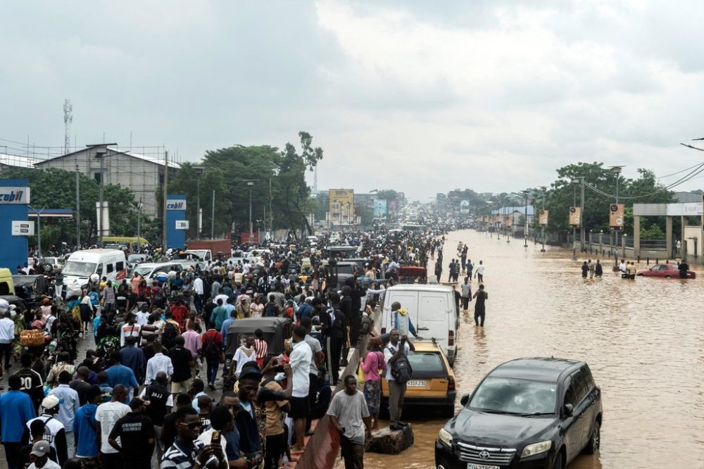 People walk through the flooded streets of Kinshasa, Democratic Republic of Congo Sunday, April 6, 2025. (AP Photo/Samy Ntumba Shambuyi)