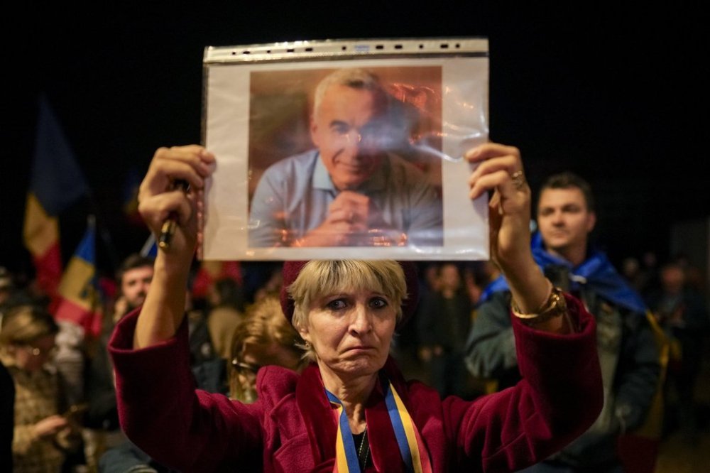A woman holds a portrait of Calin Georgescu during a protest after Romania's Constitutional Court upholded a ban on his candidacy in the presidential election rerun, in Bucharest, Romania, Tuesday, March 11, 2025. (AP Photo/Vadim Ghirda)