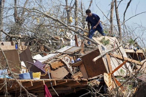 Family friend Trey Bridges, 16, climbs a mountain of tornado debris to help the Blansett family recover items not destroyed by Saturday's tornado, Sunday, March 16, 2025, in Tylertown, Miss. (AP Photo/Rogelio V. Solis)