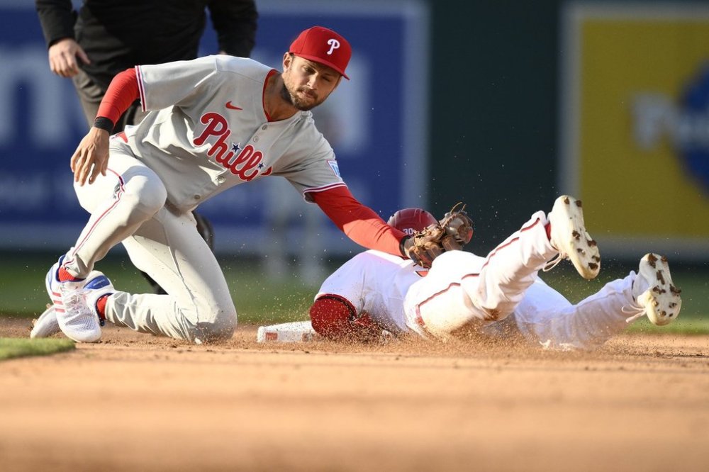 Philadelphia Phillies shortstop Trea Turner, left, tags out Washington Nationals' Jacob Young, right, as he attempted to steal second base in the sixth inning of an opening-day baseball game, Thursday, March 27, 2025, in Washington. (AP Photo/Nick Wass)