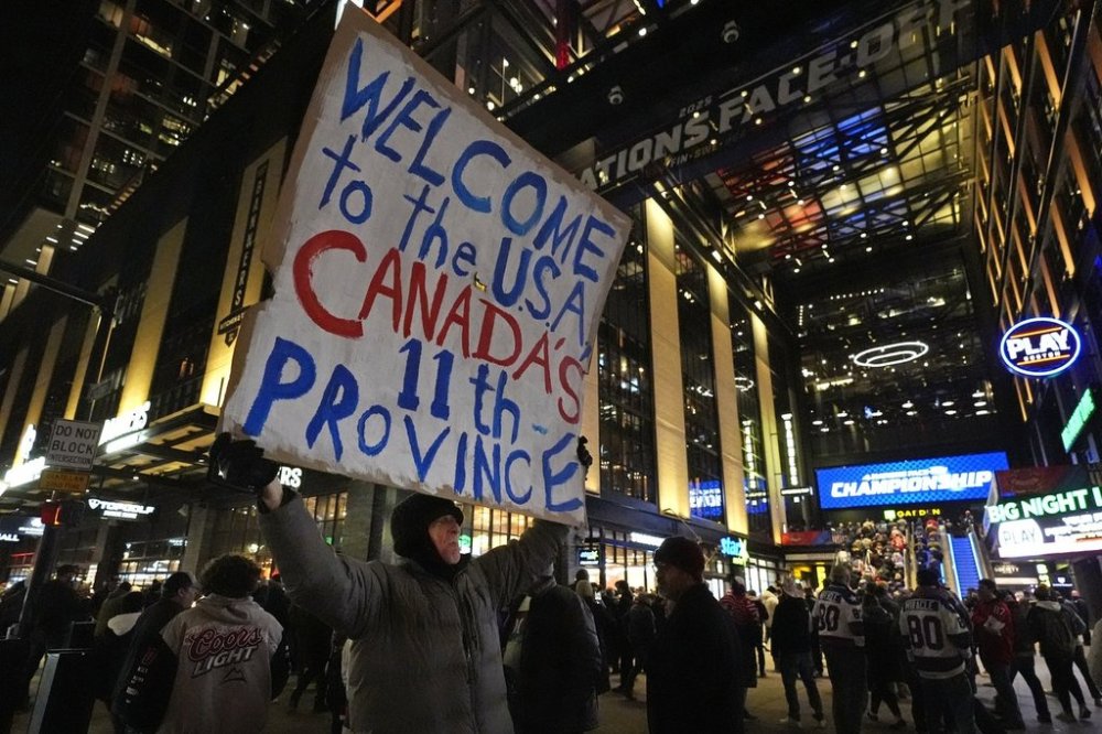 FILE - As fans enter the Boston Garden, a man holds a sign on the sidewalk prior to the 4 Nations Face-Off championship hockey game between the United States and Canada,Feb. 20, 2025, in Boston. (AP Photo/Charles Krupa, File)