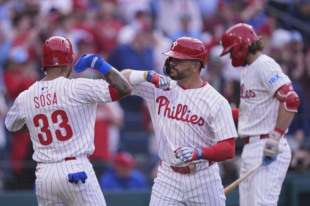 Philadelphia Phillies' Kyle Schwarber, center, celebrates with Edmundo Sosa (33) after hitting a two-run home run off Colorado Rockies pitcher Victor Vodnik (not shown) during the seventh inning of the Phillies' home-opener baseball game, Monday, March 31, 2025, in Philadelphia. (AP Photo/Matt Rourke)