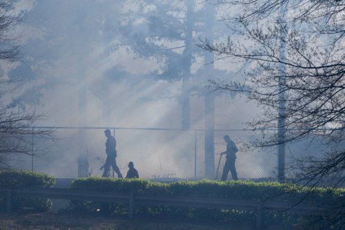 Firefighters work to extinguish a fire in a wooded area behind a Walmart, Wednesday, March 19, 2025, in Little Rock, Ark. (Adam Vogler/Arkansas Democrat-Gazette via AP)