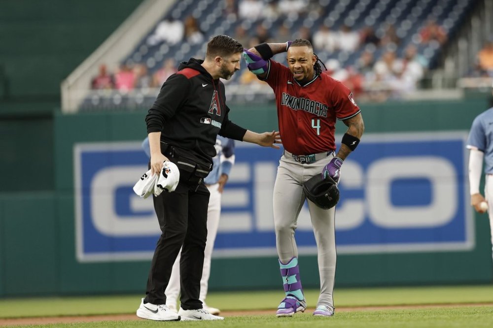 Arizona Diamondbacks' Ketel Marte (4) is checked by a trainer after an apparent leg injury after hitting a double off Washington Nationals pitcher Jake Irvin during the first inning of a baseball game in Washington, Friday, April 4, 2025. (AP Photo/Terrance Williams)