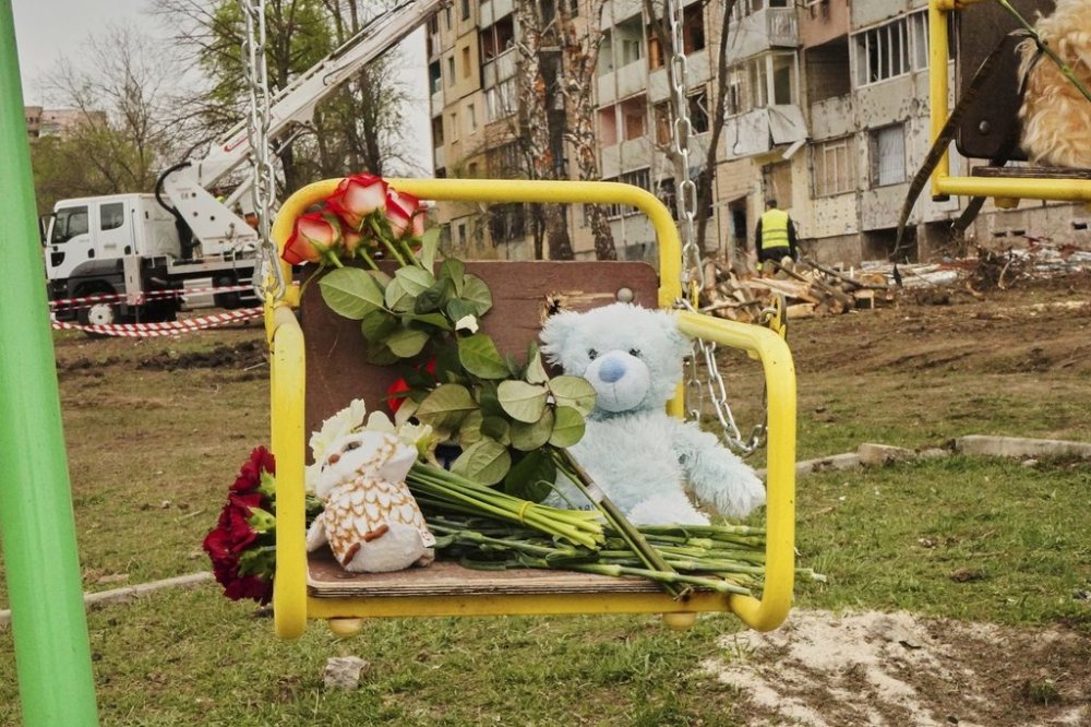 Flowers and toys left on a swing seat to commemorate victims killed in Russia's missile attack on Friday, at a children play area near the damaged apartment buildings, in Kryvyi Rih, Ukraine, Saturday, April 5, 2025. (AP Photo)
