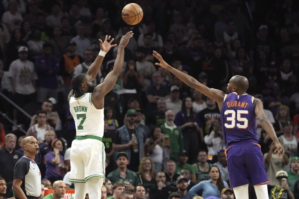 Boston Celtics guard Jaylen Brown (7) shoots a 3-pointer over Phoenix Suns forward Kevin Durant (35) during the first half of an NBA basketball game Wednesday, March 26, 2025, in Phoenix. (AP Photo/Ross D. Franklin)