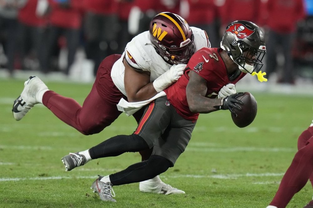 FILE- Tampa Bay Buccaneers running back Bucky Irving, right, runs against Washington Commanders defensive tackle Jonathan Allen during the second half of an NFL wild-card playoff football game in Tampa, Fla., Jan. 12, 2025. (AP Photo/Chris O'Meara, file)