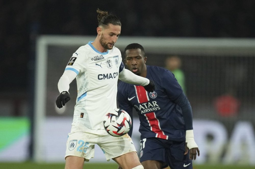 Marseille's Adrien Rabiot, left, challenges for the ball with PSG's Willian Pacho during the French League One soccer match between Paris Saint Germain and Marseille at Parc des Princes stadium in Paris, Sunday, March 16, 2025. (AP Photo/Christophe Ena)