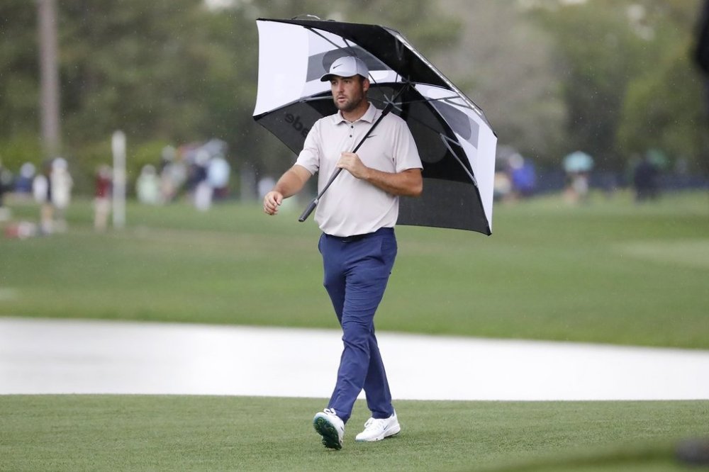Scottie Scheffler walks onto the 17th green under an umbrella in the rain during the first round of the Houston Open golf tournament, Thursday, March 27, 2025, in Houston. (AP Photo/Michael Wyke)
