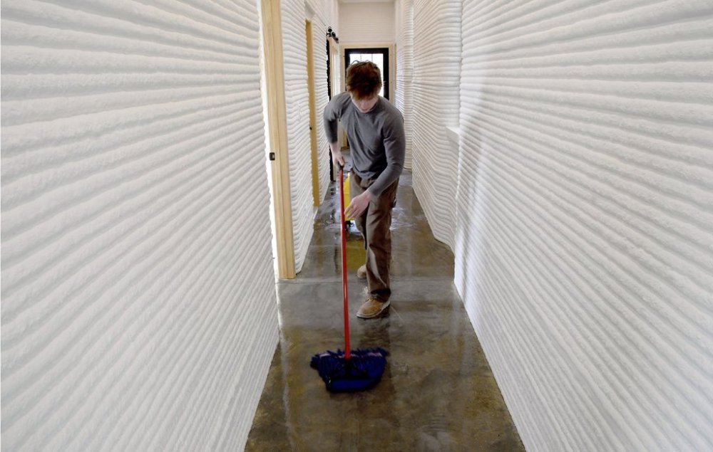 David Leach mops the floor of a 3D-printed concrete home built by VeroTouch in Buena Vista, Colo., on Feb. 19, 2025. (AP Photo/Thomas Peipert)