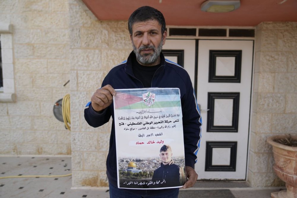 Khalid Ahmad holds a poster of his 17-year-old son, Waleed, who died in an Israeli prison, that reads in Arabic,