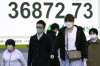 People walk in front of an electronic stock board showing Japan's Nikkei index at a securities firm Monday, March 10, 2025, in Tokyo. (AP Photo/Eugene Hoshiko)