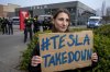 A protester holds a placard during a Tesla Takedown Global Day protest in front of a Tesla dealership, in Berlin, Saturday, March 29, 2025. (AP Photo/Ebrahim Noroozi)