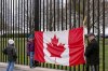 Toronto residents Douglas Bloomfield, from right, his son Phoenix and wife Ame, who are on vacation in Washington, hold a Canadian flag and an ice hockey stick to show their support for Canada regarding trade tariffs in front of the White House in Washington, Thursday, March 13, 2025. (AP Photo/Ben Curtis)