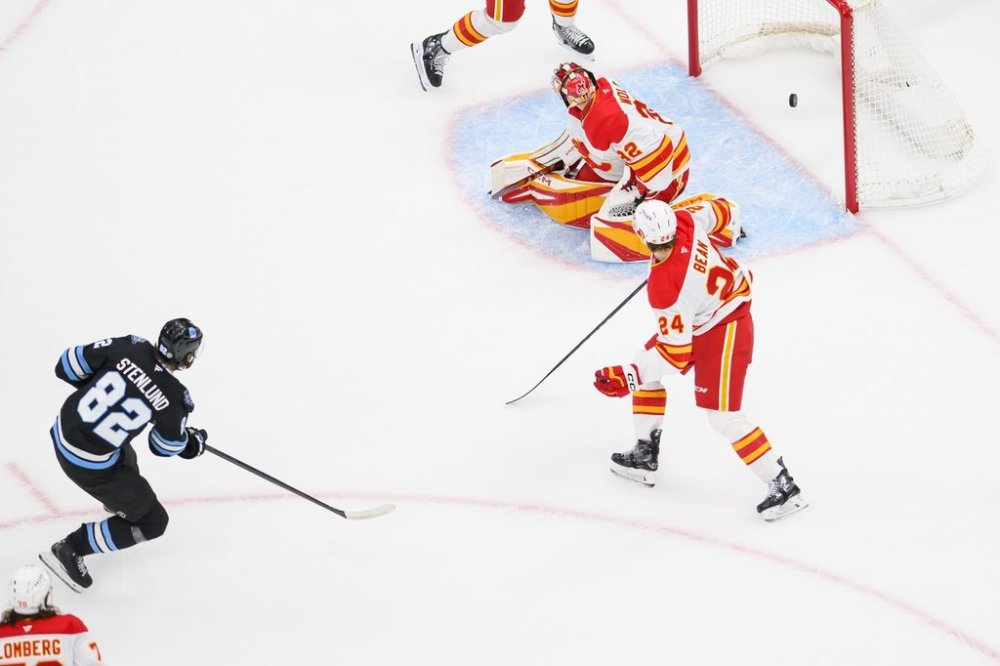 Utah Hockey Club centre Kevin Stenlund (82) shoots and scores a goal past Calgary Flames goaltender Dustin Wolf (32) during the first period of an NHL hockey game, Tuesday, April 1, 2025, in Salt Lake City. (AP Photo/Tyler Tate)
