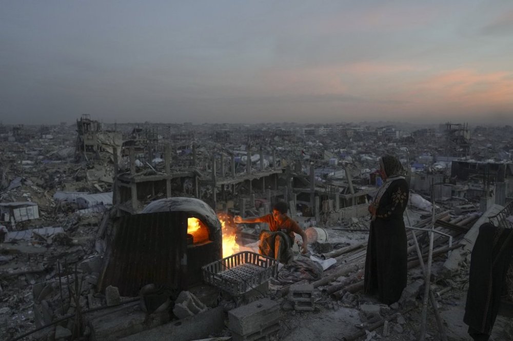 Ali Marouf and his mother Aisha cook on a fire on the roof of their house, which was destroyed by the Israeli army's air and ground offensive, in Jabaliya, Gaza Strip, on Monday, March 17, 2025. (AP Photo/Jehad Alshrafi)