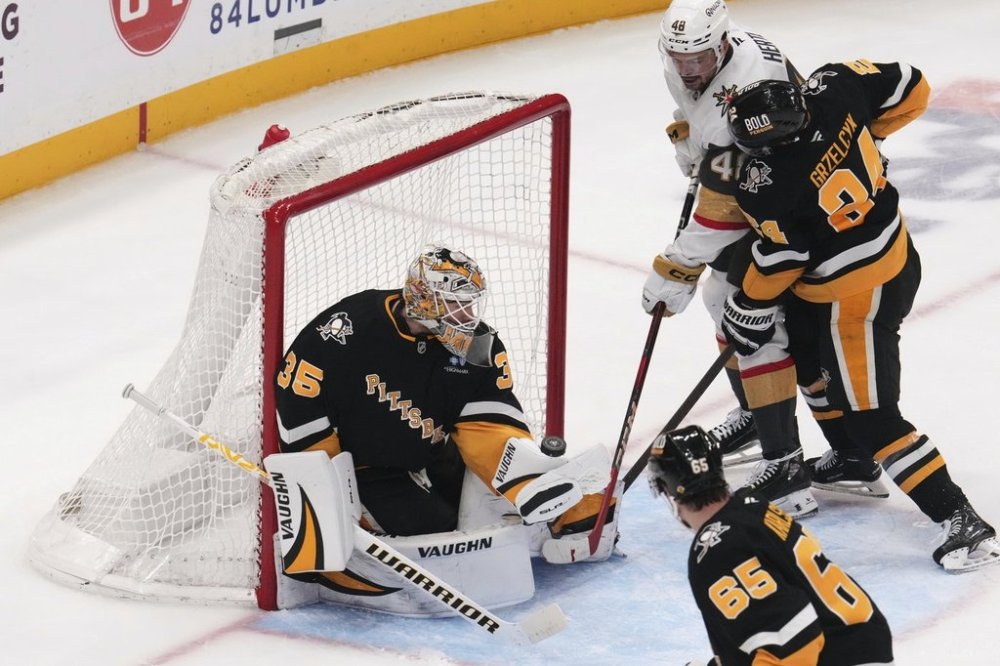 Pittsburgh Penguins goaltender Tristan Jarry (35) blocks a shot by Vegas Golden Knights' Tomas Hertl (48) with Matt Grzelcyk defending during the third period of an NHL hockey game in Pittsburgh, Tuesday, March 11, 2025. (AP Photo/Gene J. Puskar)