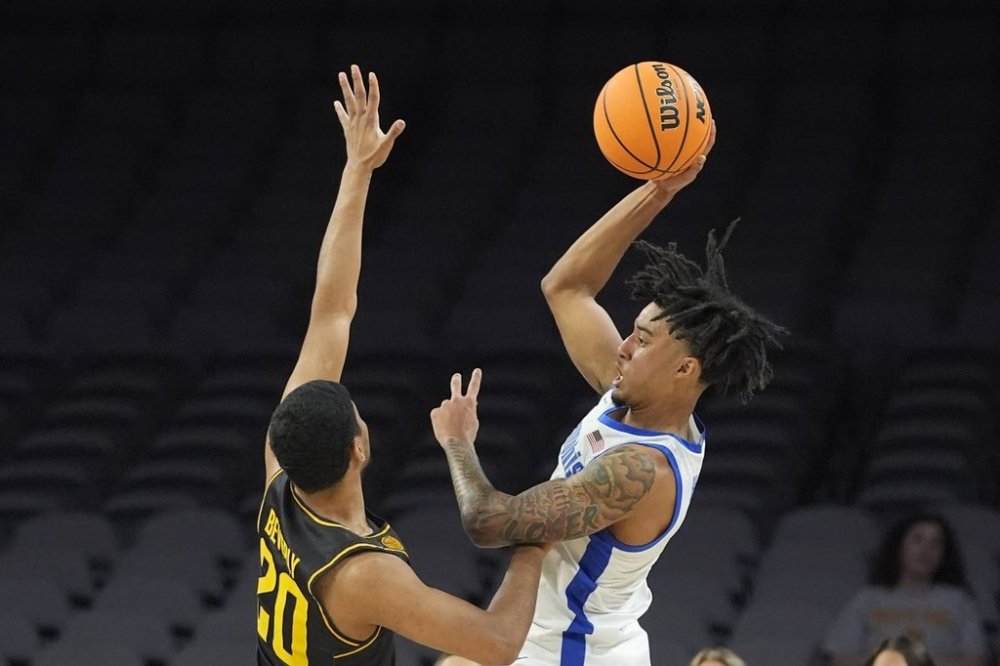 Memphis guard PJ Haggerty, right, shoots against Wichita State guard Harlond Beverly (20) during the first half of an NCAA college basketball game in the quarterfinals of the American Athletic Conference tournament in Fort Worth, Texas, Friday, March 14, 2025. (AP Photo/LM Otero)