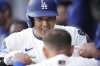 Los Angeles Dodgers' Shohei Ohtani, top, celebrates with Miguel Rojas after hitting a solo home run during the seventh inning of a home-opening baseball game against the Detroit Tigers, Thursday, March 27, 2025, in Los Angeles. (AP Photo/Mark J. Terrill)