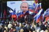 FILE - People watch as Russian President Vladimir Putin delivers a speech after signing treaties for four regions of Ukraine to join Russia in the Moscow's Kremlin, during a meeting in Sevastopol, Crimea, on Sept. 30, 2022. (AP Photo, File)