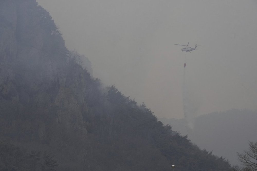 A helicopter dumps water on a mountain after a wildfire broke out in Cheongsong, South Korea, Thursday, March 27, 2025. (AP Photo/Ahn Young-joon)