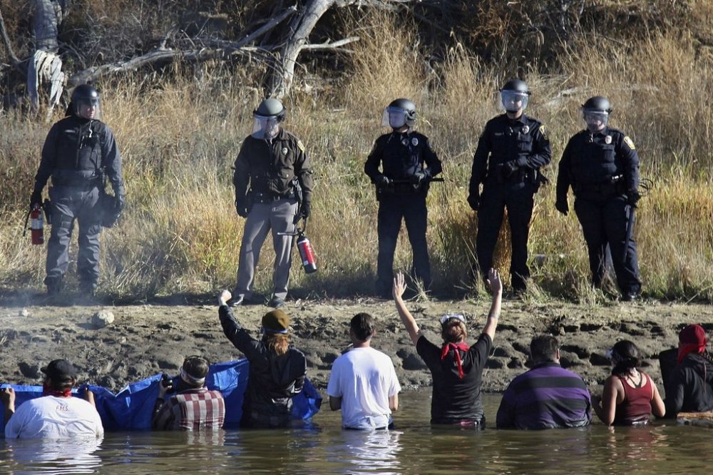 FILE - Protestors demonstrating against the expansion of the Dakota Access Pipeline wade in cold creek waters confronting local police, near Cannon Ball, N.D., Nov. 2, 2016. (AP Photo/John L. Mone, File)
