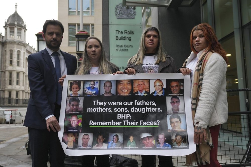 Mariana dam disaster victims, from right, Pamela Fernandes, Gelvana Rodrigues, Monica dos Santos and former interim mayor of Mariana, Juliano Duarte, holding a banner outside the High Court, in London, Thursday, March 13, 2025. (AP Photo/Kin Cheung)