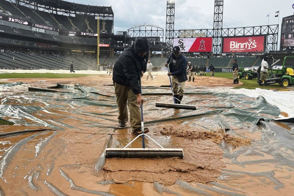The grounds crew works on the field during a rain delay in the seventh inning of a baseball game between the Los Angeles Angels and the Chicago White Sox in Chicago, Sunday, March 30, 2025. (AP Photo/Nam Y. Huh)