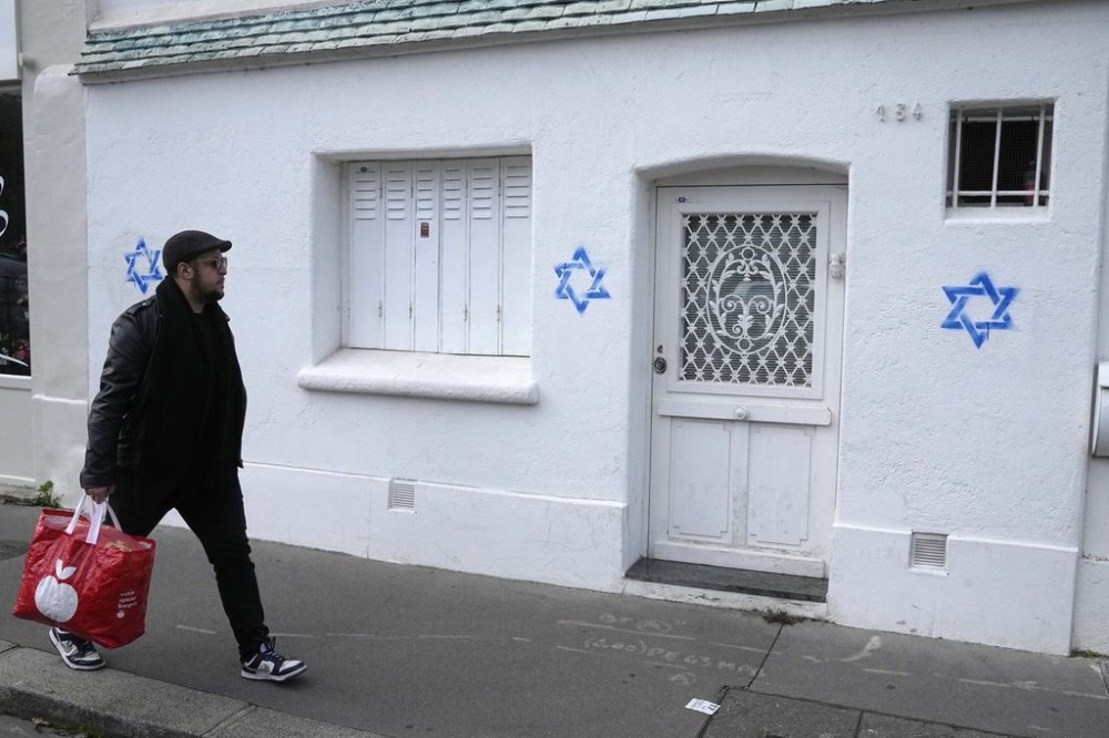 FILE - A man walks by Stars of David tagged on a wall in Paris, Oct. 31, 2023. (AP Photo/Michel Euler, File)