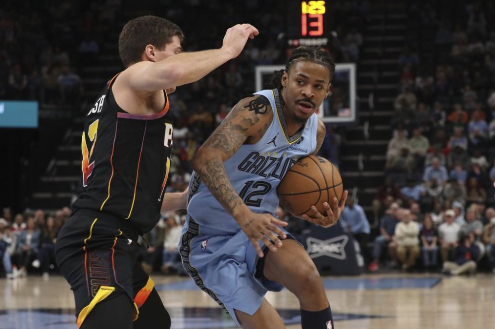 Phoenix Suns guard Collin Gillespie, left, defends against Memphis Grizzlies guard Ja Morant, right, in the first half of an NBA basketball game Monday, March 10, 2025, in Memphis, Tenn. (AP Photo/Nikki Boertman)