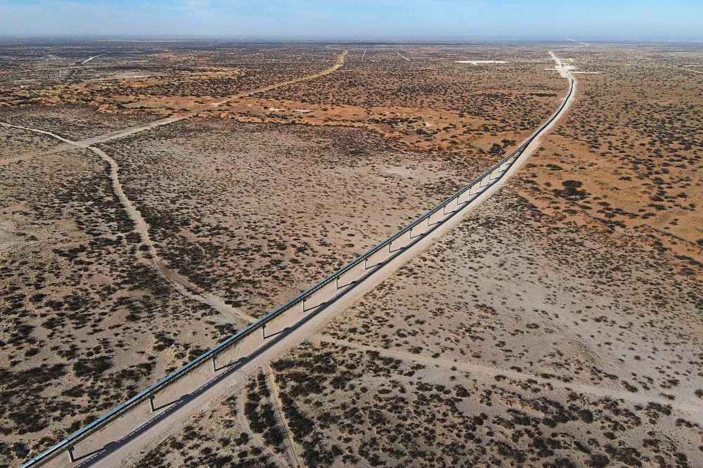 With New Mexico seen at a distance, a 42-mile conveyor belt by Atlas Energy carries sand needed for hydraulic fracturing Wednesday, Feb. 26, 2025, in Kermit, Texas. (AP Photo/Julio Cortez)
