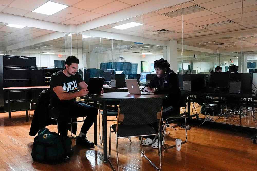 Damon LaSalle, left, studies with a teammate before volleyball practice at New Jersey City University, Friday, Feb. 21, 2025, in Jersey City, N.J. (AP Photo/Julia Demaree Nikhinson)