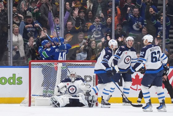 Vancouver Canucks' Nils Hoglander, back from left to right, Brock Boeser and Elias Pettersson celebrate Hoglander's goal against Winnipeg Jets goalie Connor Hellebuyck as Dylan DeMelo (2), Dylan Samberg (54) and Nino Niederreiter (62) look on, during the first period of the March 18 game. (Darryl Dyck / The Canadian Press files)