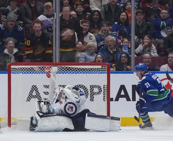 Vancouver Canucks' Nils Hoglander scores on Connor Hellebuyck during the first period in Vancouver Tuesday night. (Darryl Dyck / The Canadian Press)