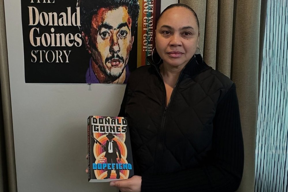 Donna Sailor poses next to poster of upcoming documentary about the life of her father and urban literature writer Donald Goines on Wednesday, March 12, 2025 in Detroit. (AP Photo/Corey Williams)