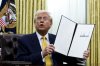 President Donald Trump holds a signed executive order as he speaks in the Oval Office of the White House in Washington on Friday, March 7, 2025. THE CANADIAN PRESS/AP — Pool