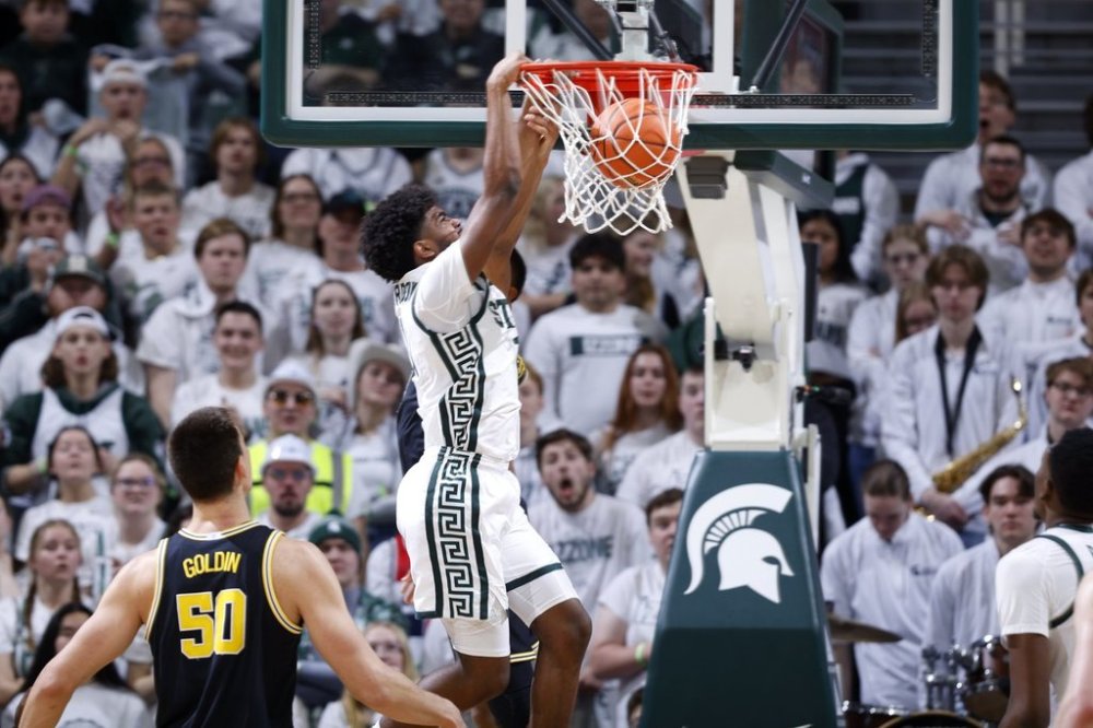 Michigan State guard Jase Richardson, center, dunks against Michigan center Vladislav Goldin (50) during the first half of an NCAA college basketball game, Sunday, March 9, 2025, in East Lansing, Mich. (AP Photo/Al Goldis)