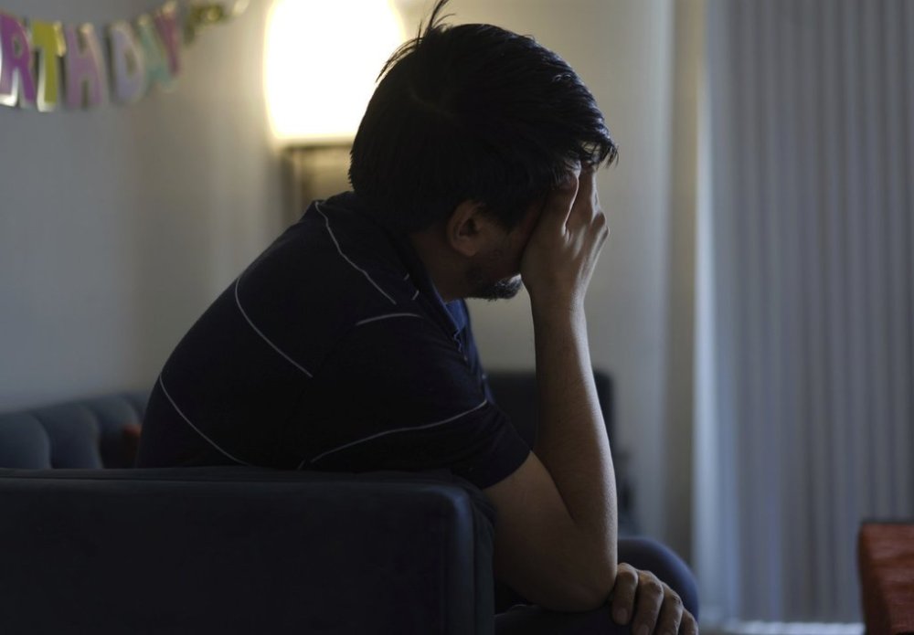 Rahmani, who has been experiencing anxiety and depression since the Trump administration cut federal funding for refugee programs, rubs his eyes while sitting in his apartment in Laurel, Md., Monday, March 3, 2025. (AP Photo/Jessie Wardarski)