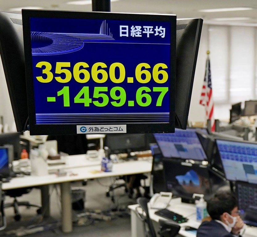 A currency trader works under an electronic stock board at a foreign currency trading firm in Tokyo Monday, March 31, 2025. (Kyodo News via AP)