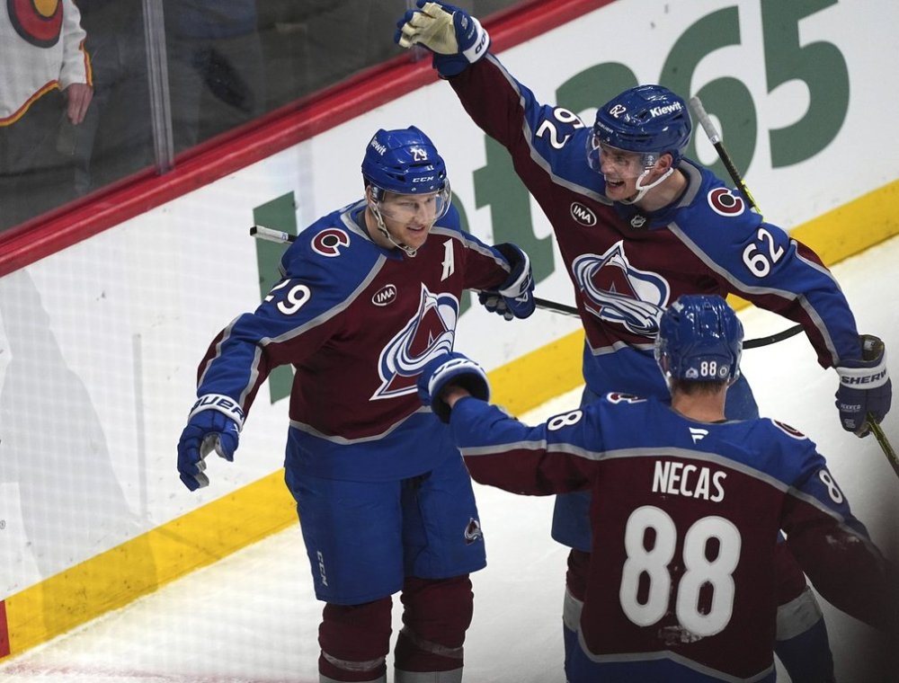 Colorado Avalanche center Nathan MacKinnon, left, is congratulated after scoring a goal by left wing Artturi Lehkonen, back right, and center Martin Necas in the third period of an NHL hockey game against the New Jersey Devils Wednesday, Feb. 26, 2025, in Denver. (AP Photo/David Zalubowski)