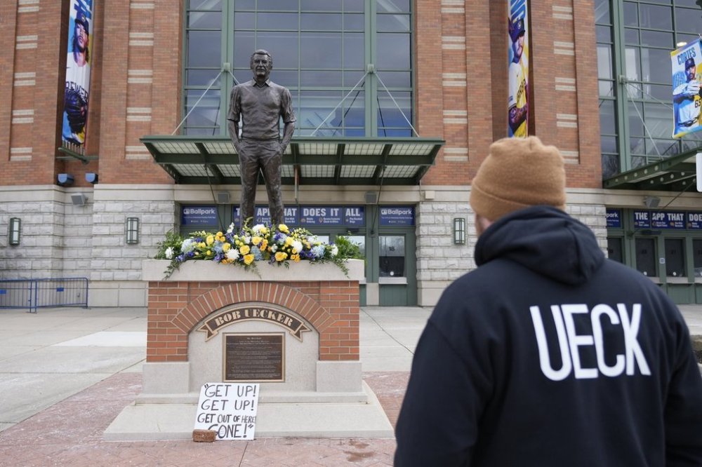 A Milwaukee Brewers fan observes the memorial at the Bob Uecker statue in front of American Family Field prior to a baseball game between the Milwaukee Brewers and the Kansas City Royals on Opening Day Monday, March 31, 2025, in Milwaukee. (AP Photo/Kayla Wolf)
