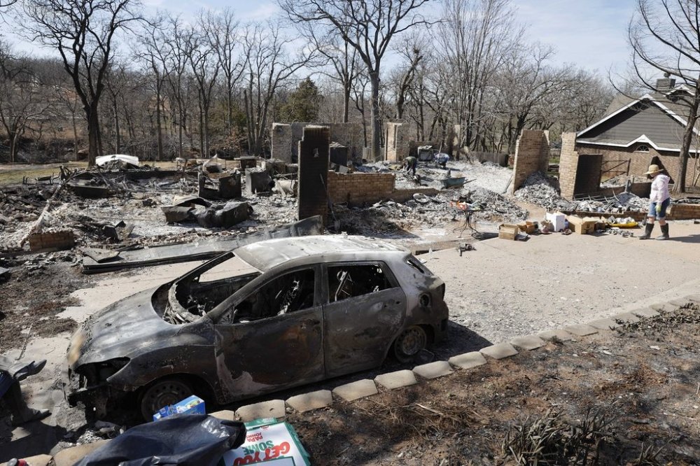 Andrine Shufran, right, looks through the ashes that are left of her home in the Hidden Oaks neighborhood in Stillwater, Okla., Monday, March 17, 2025, after wildfires burned through the area Friday. (AP Photo/Alonzo Adams)