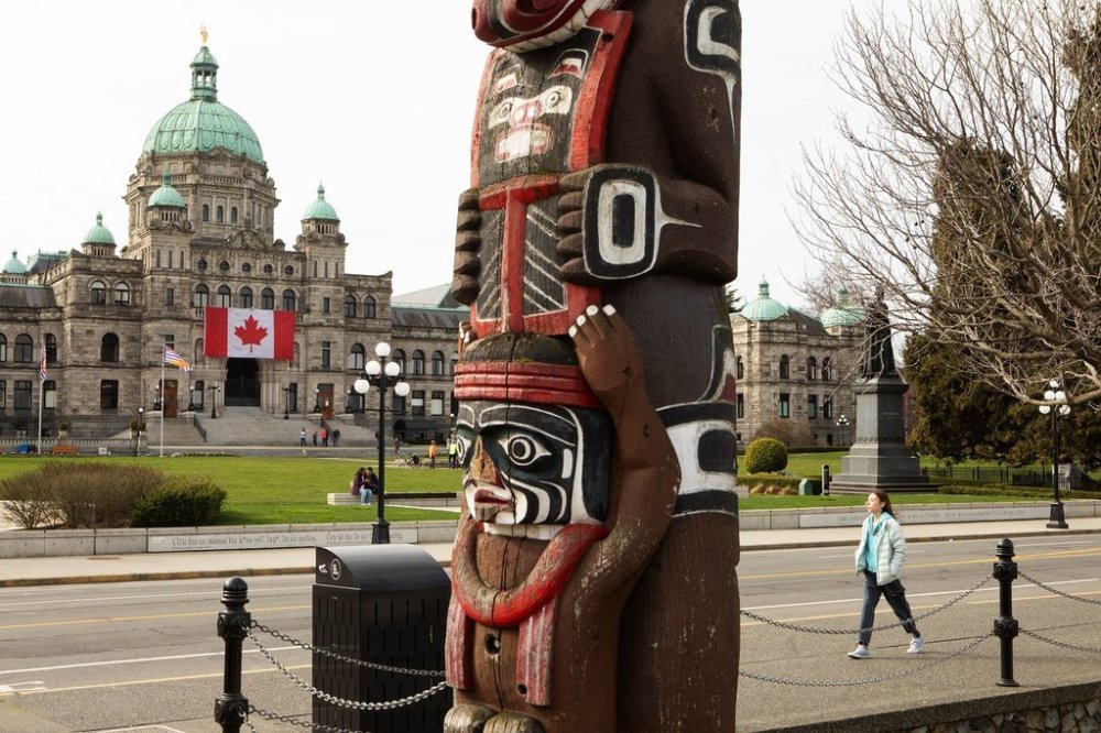 A Canadian flag hangs over the ceremonial entrance at the legislature as people walk about in Victoria, Friday, March 7, 2025. THE CANADIAN PRESS/Chad Hipolito