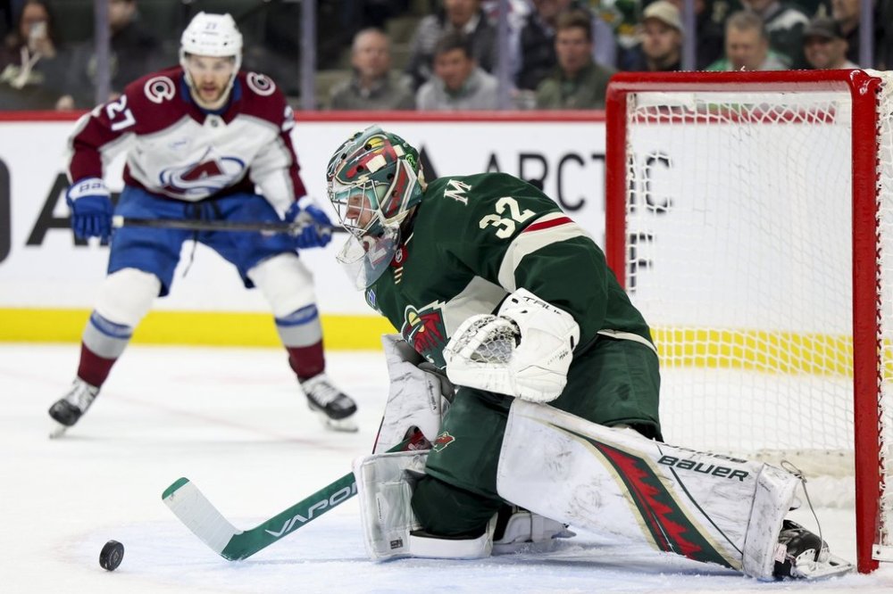 Minnesota Wild goaltender Filip Gustavsson (32) saves the puck while Colorado Avalanche left wing Jonathan Drouin, left, looks on during the second period of an NHL hockey game, Tuesday, March 11, 2025, in St. Paul, Minn. (AP Photo/Ellen Schmidt)