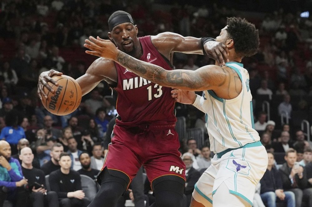 Miami Heat center Bam Adebayo (13) dribbles the ball as Charlotte Hornets forward Miles Bridges (0) defends during the first half of an NBA basketball game, Monday, March 10, 2025, in Miami. (AP Photo/Marta Lavandier)