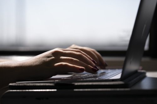 FILE - This May 18, 2021, photo shows a person typing on a laptop on a train in New Jersey. (AP Photo/Jenny Kane, File)