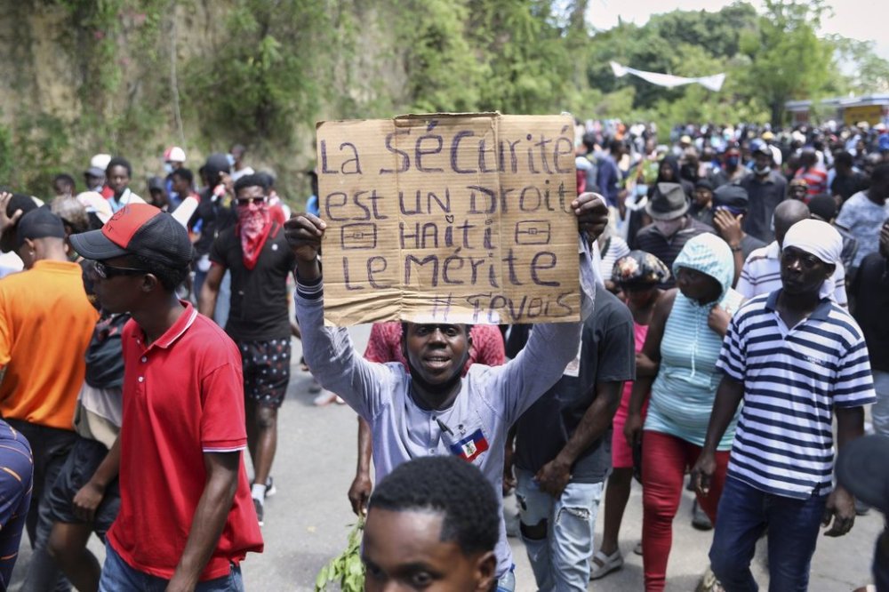 A protester holds up a sign that reads in French,