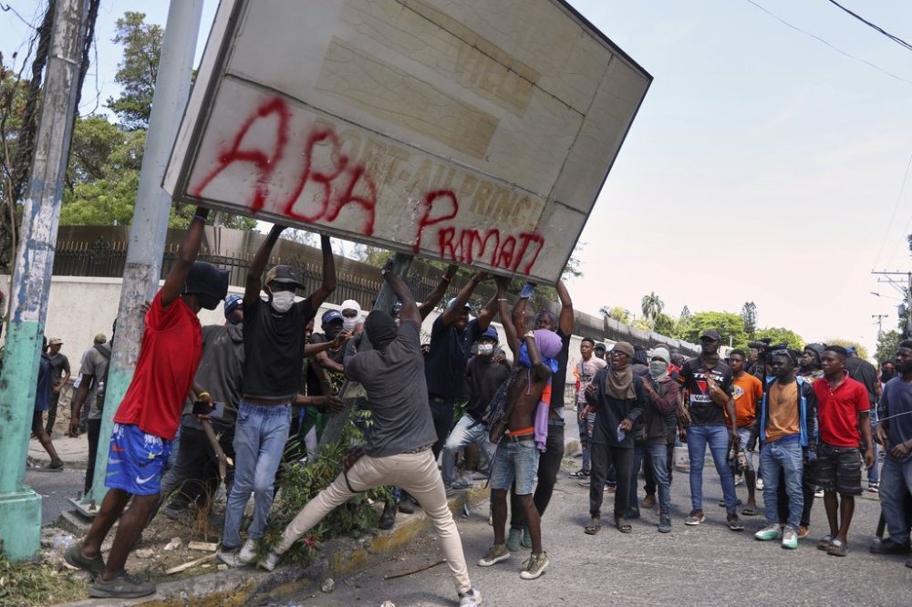 Protesters try to pull down a sign during a protest against insecurity in Port-au-Prince, Haiti, Wednesday, April 2, 2025. (AP Photo/Odelyn Joseph)