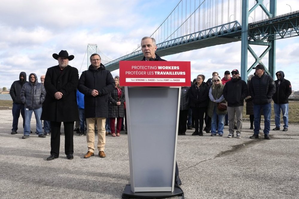 Unifor auto workers stand behind Liberal Leader Mark Carney as he speaks during a campaign stop at the Ambassador Bridge in Windsor, Ont., on Wednesday, March 26, 2025. THE CANADIAN PRESS/Frank Gunn
